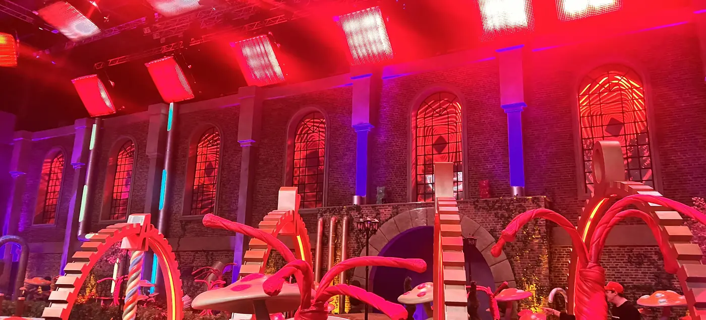 Red and blue stage lighting over a themed set inside a heritage brick studio