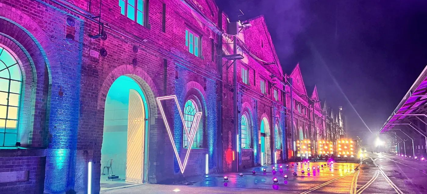 Exterior brick warehouse washed in magenta and teal light at night