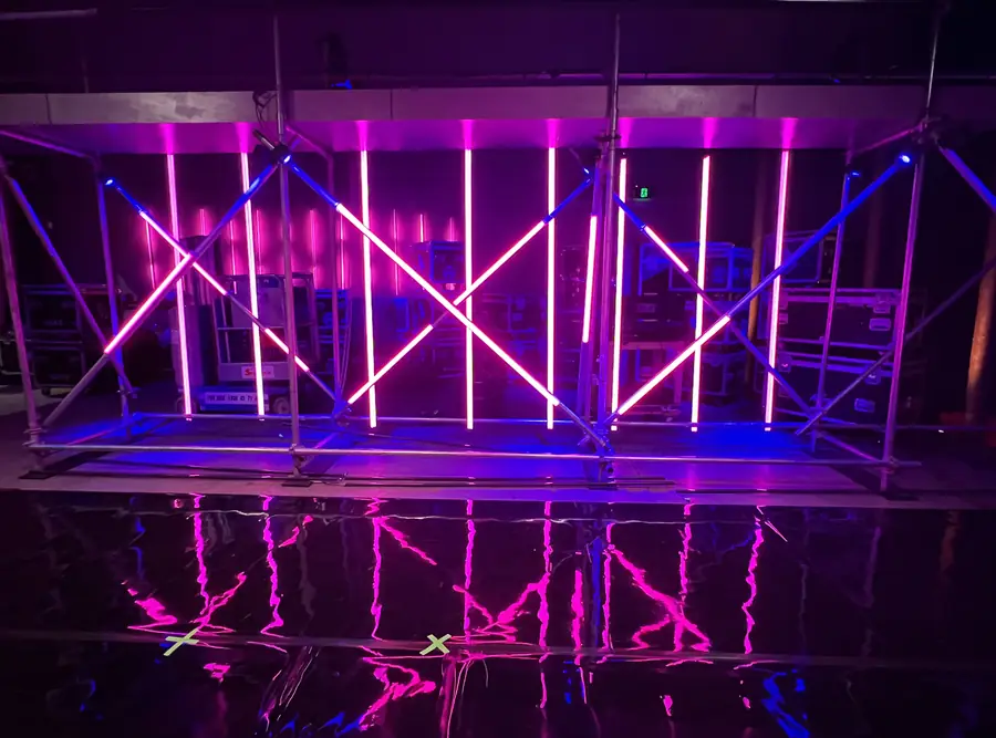 Reflected pink and blue light tubes on a water-covered stage